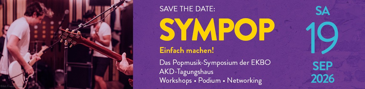 Eine Musikgruppe in einem rötlich ausgeleuchteten Proberaum. Im Vordergrund ist der Hals einer E-Gitarre zu sehen, im Hintergrund spielen zwei Musiker.